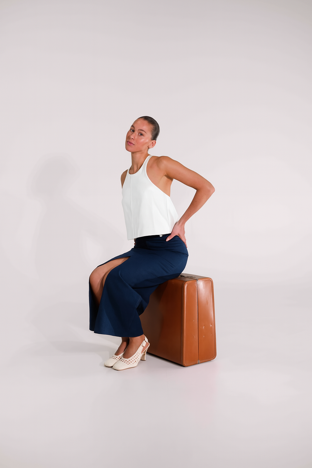 Woman wearing white halter neck top with navy maxi skirt in white studio